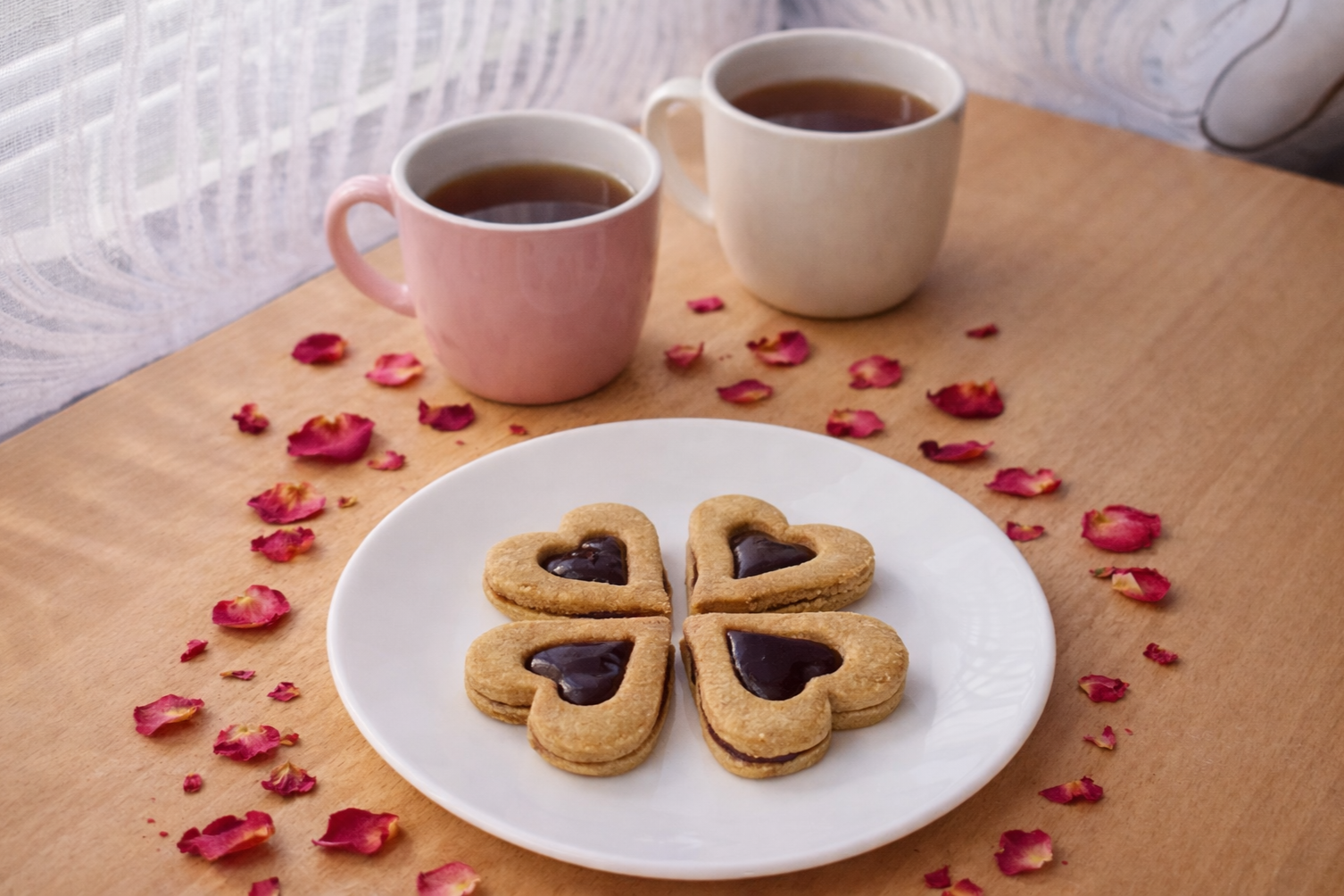 Linecké cukroví bez rafinovaného cukru ve tvaru srdíček plněné marmeládou, podávané na bílém talíři s čajem